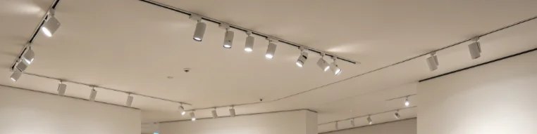 Band of white track spotlights along a gallery ceiling